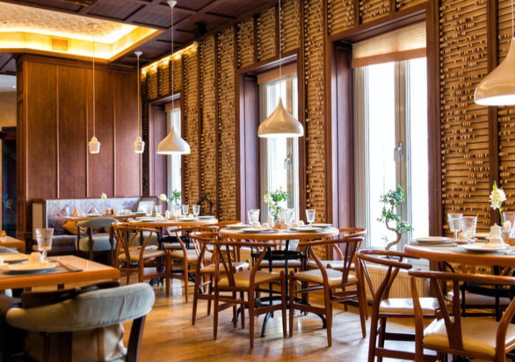 um restaurante com mesas e cadeiras de madeira e janelas em Hotel Royal Pacific Near Delhi International Airport em Nova Deli