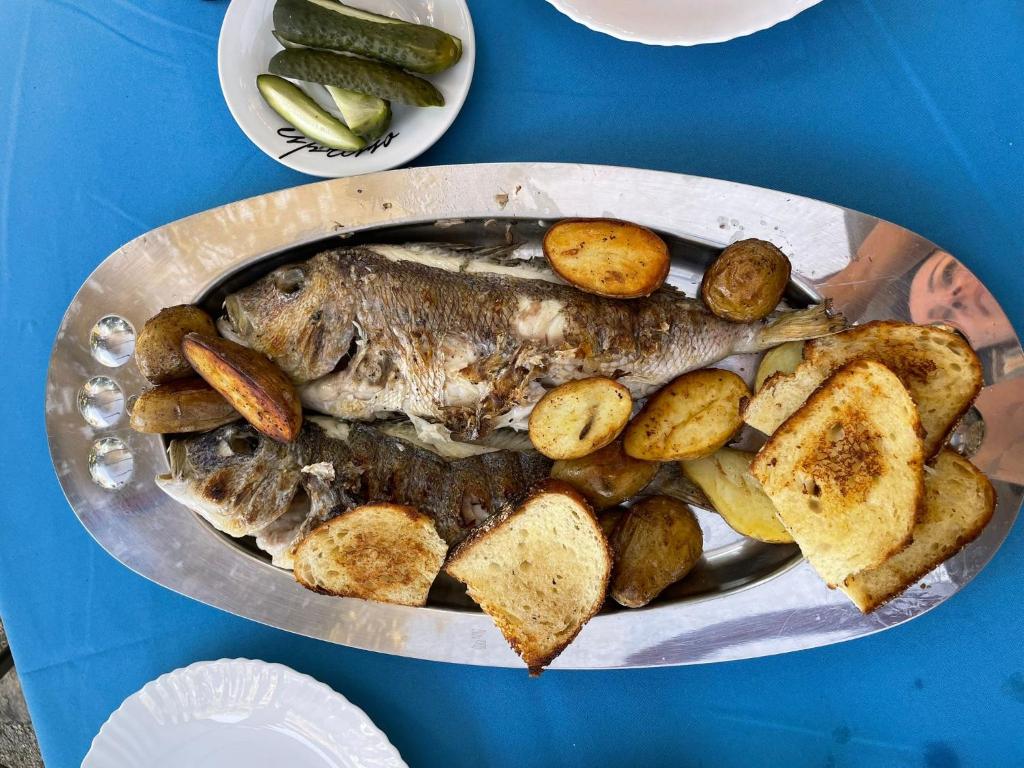 talerz ryb, ziemniaków i ogórków na stole w obiekcie Isolated, 30m to sea, Viktoria s cottage w mieście Kali