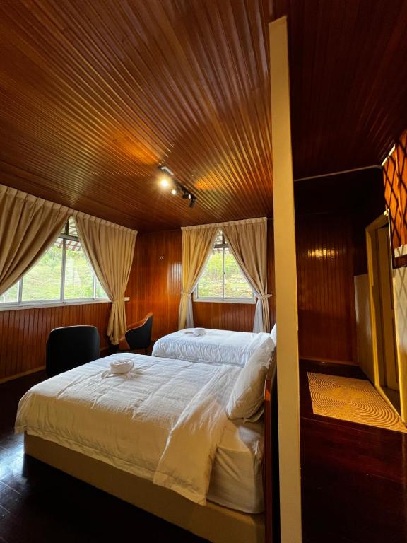 a bedroom with a large bed with a wooden ceiling at 3 Retro-Antique Inspired Interconnected Family Rooms at Country Lodge - Eco Valley Retreat 豐之谷 in Tawau