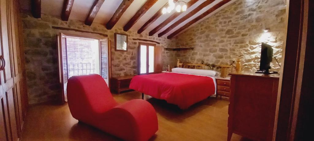 a bedroom with a red table and a red chair at Casa rural la Posada Terra Alta Matarraña in Caseras