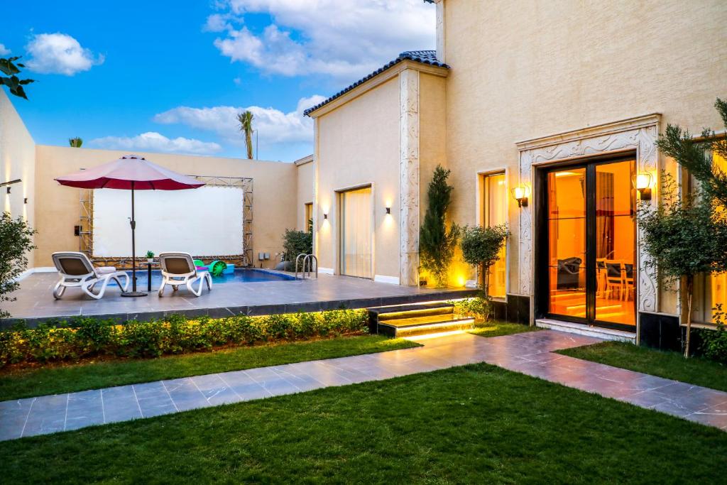 Casa con patio con mesa y sombrilla en Arjan Park Resorts en Riad