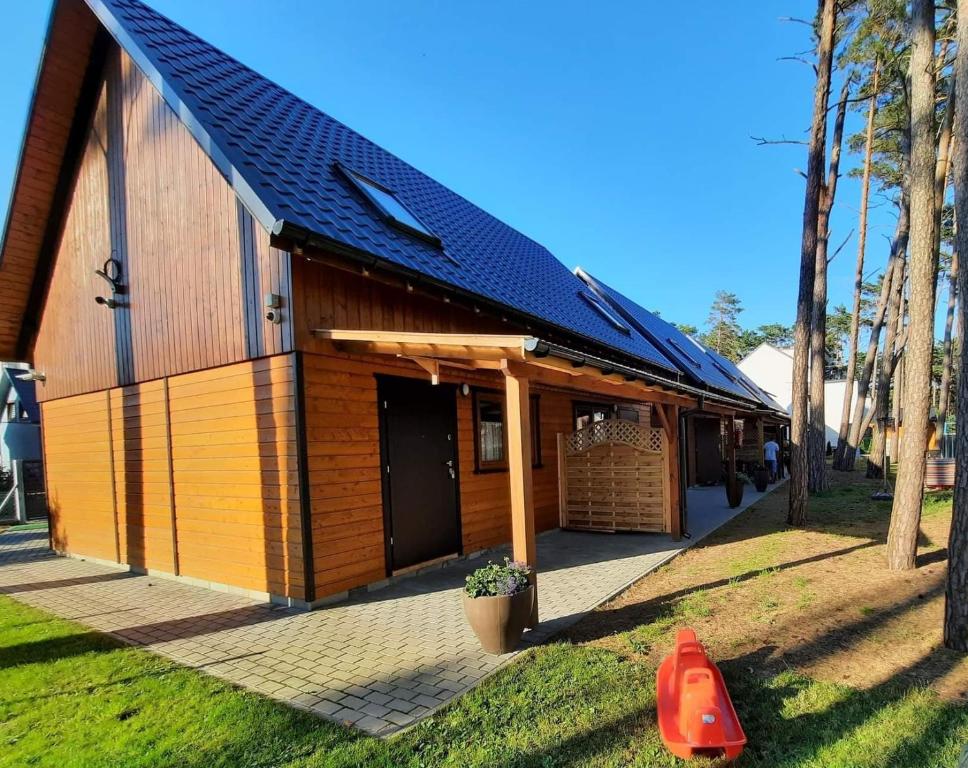 a building with a gambrel roof with a red cone at Domki Letniskowe Wiktorek Dziwnówek in Dziwnówek