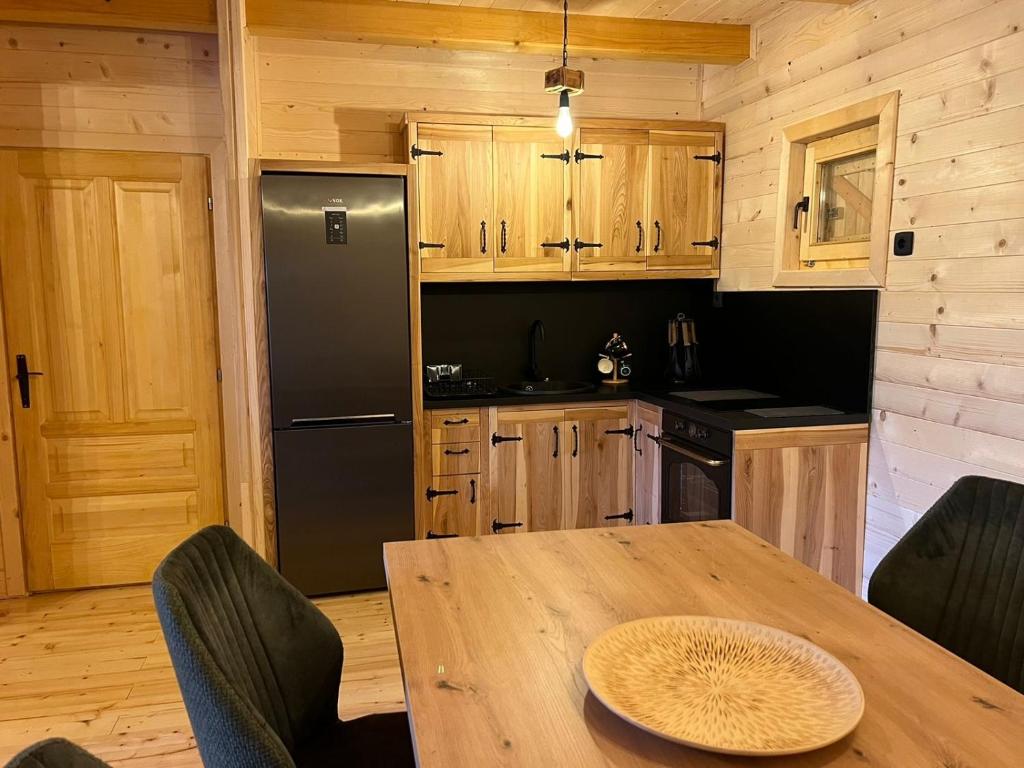 a kitchen with a table and a black refrigerator at Brvnara La Forêt in Žabljak
