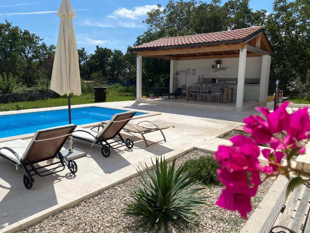 a patio with chairs and an umbrella next to a pool at Villa Yucca Istra in Labin