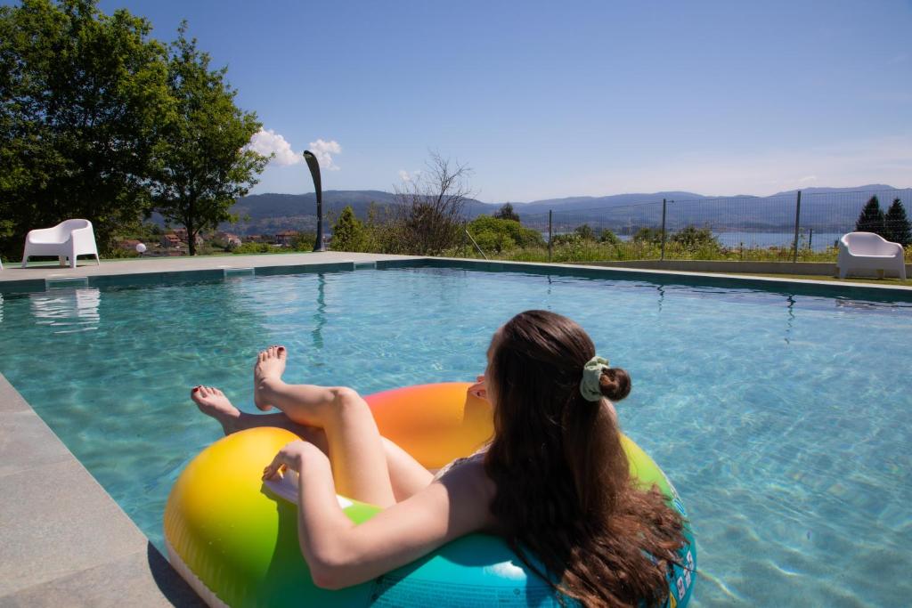 a woman laying on an inflatable ball in a swimming pool at A Oliveira in Vilaboa