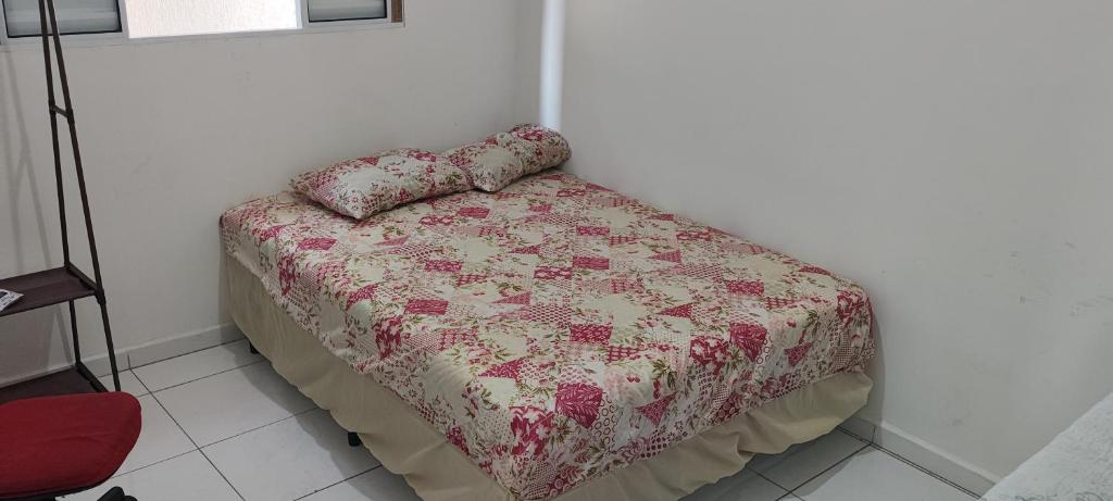 a bed with a quilt and pillows on top of it at Casa térrea com piscina e aconchegante perto da praia in Itanhaém