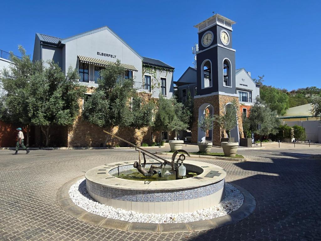 una torre del reloj con una fuente frente a un edificio en Am Weinberg Estate - The Presidential Villa - A Sanctuary of Luxury and Elegance en Windhoek