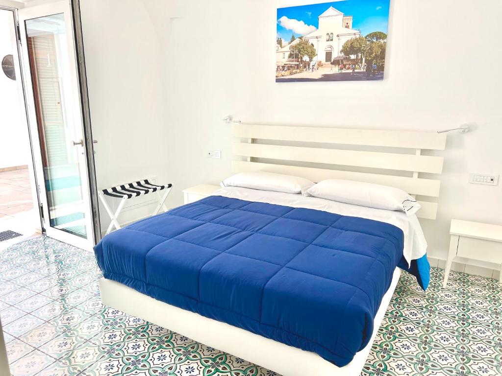 Una cama azul en una habitación blanca con en Na Stanza in centro, en Ravello