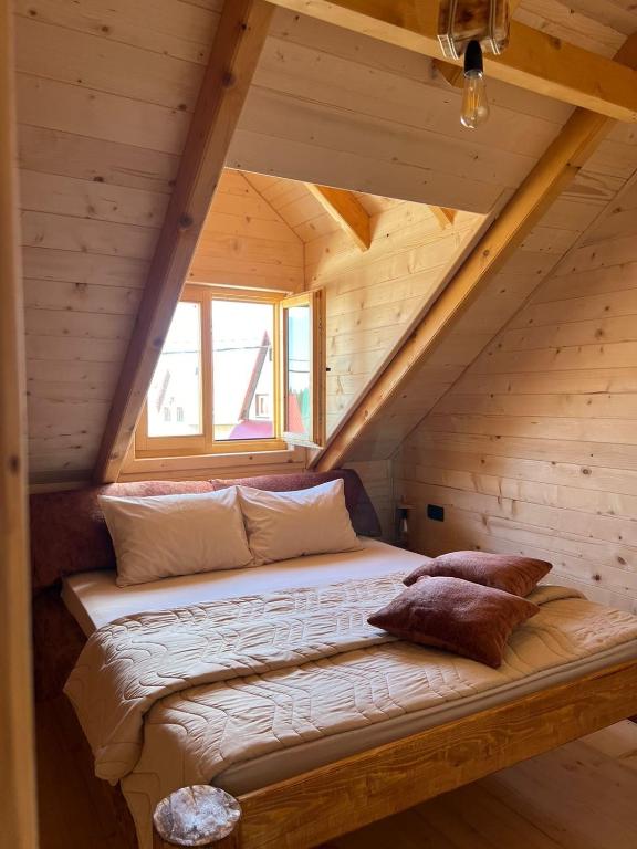 a bed in a log cabin with a window at Brvnara La Forêt in Žabljak