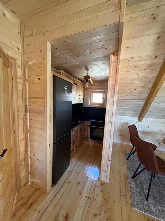 a kitchen in a log cabin with a black refrigerator at Brvnara La Forêt in Žabljak