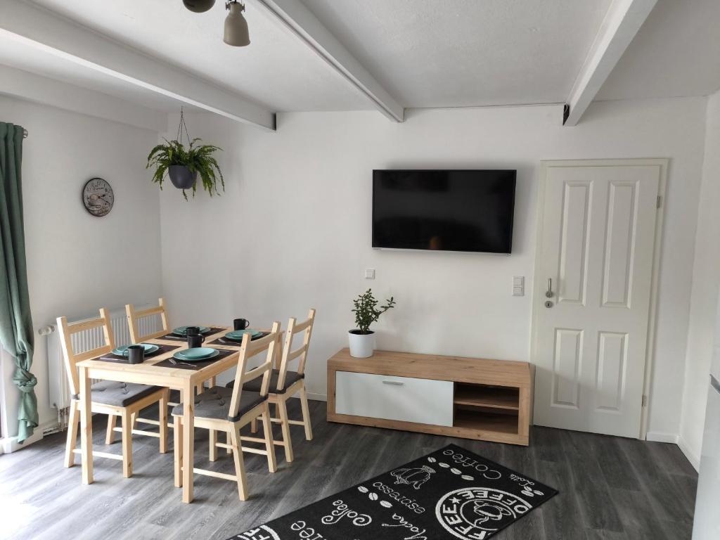a dining room with a table and chairs and a tv at Ferienwohnung am Mühlbach in Klipphausen