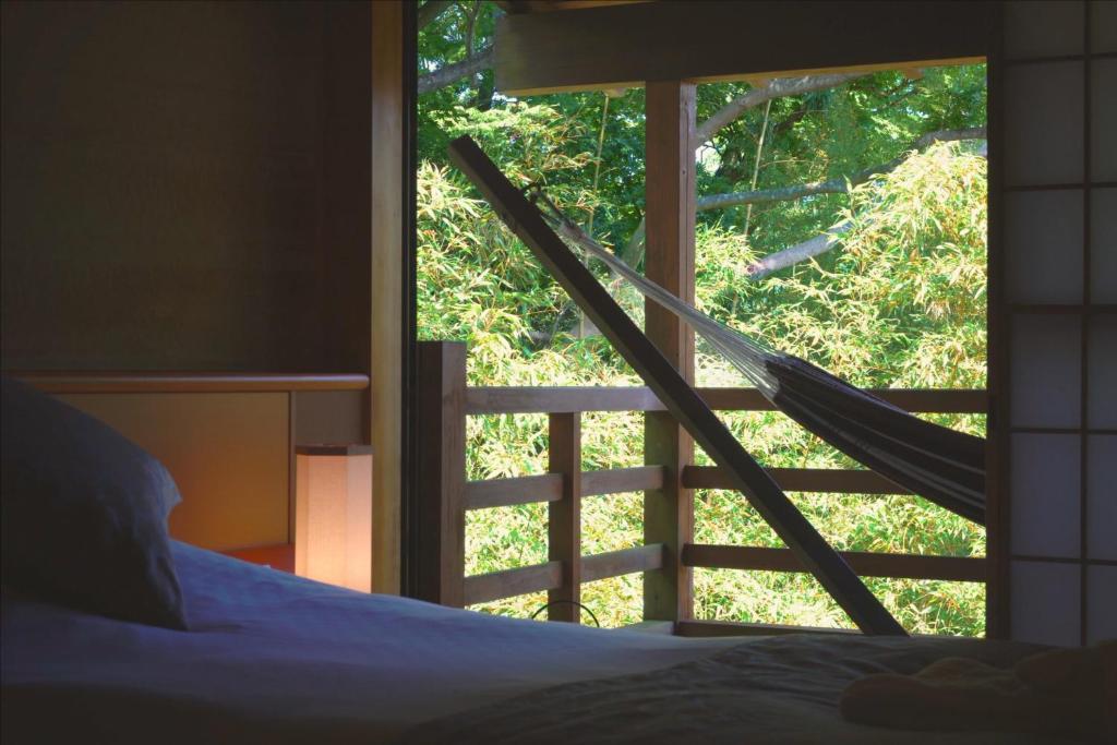 een slaapkamer met een bed en een raam met een hangmat bij Gyokusui -Adult Only- in Higashiizu