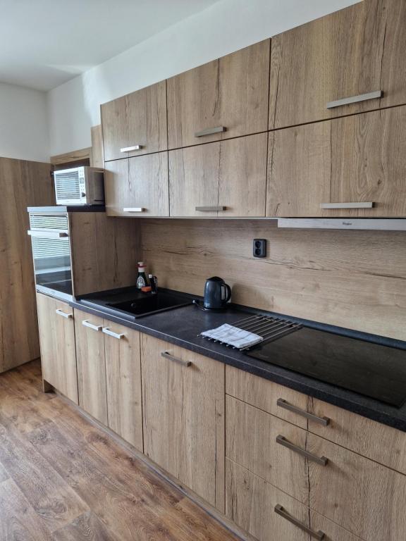 a kitchen with wooden cabinets and a black counter top at Apartmán Eliášova in Česká Lípa