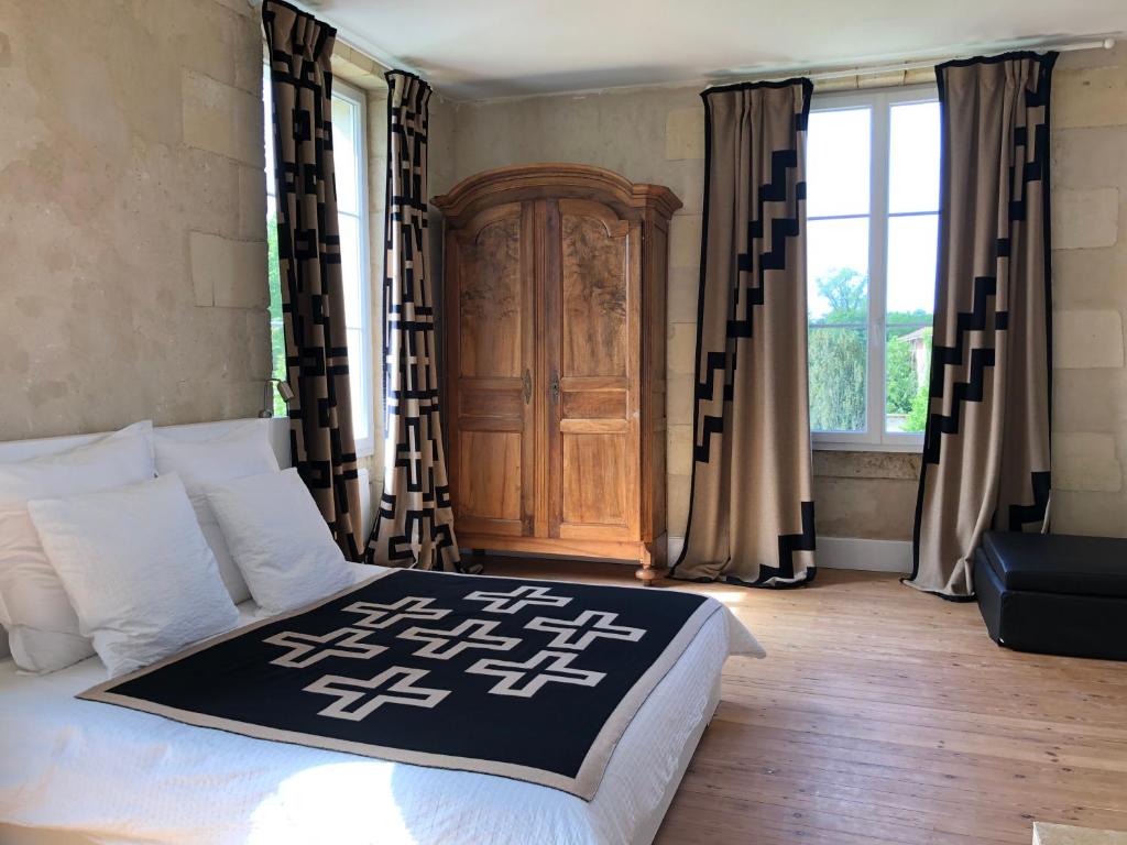 a bedroom with a bed and a wooden cabinet at Château Bernon Maison d Hotes - Piscine et sauna in Queyrac