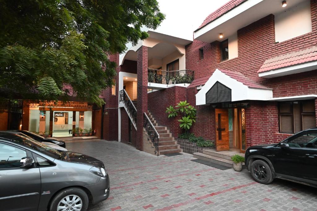 dos coches estacionados frente a un edificio de ladrillo en Little Chef Hotel, en Kānpur