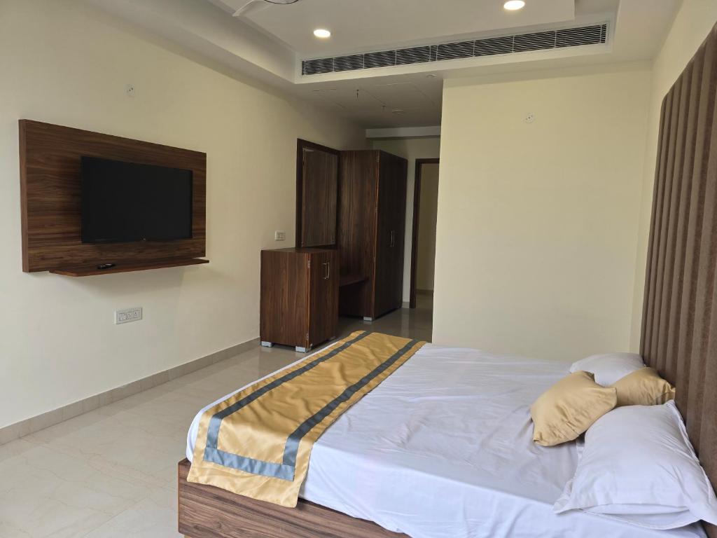 een slaapkamer met een bed en een flatscreen-tv bij MBS BANQUETS in Amritsar