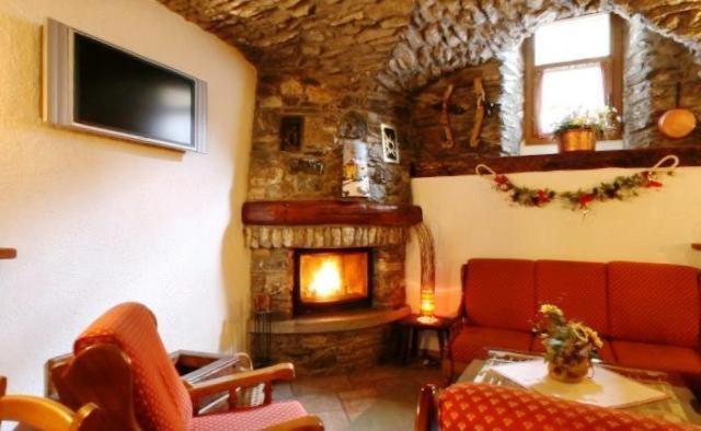 salon z kamiennym kominkiem i czerwonymi krzesłami w obiekcie Chalet Chez Nous w mieście Sauze dʼOulx