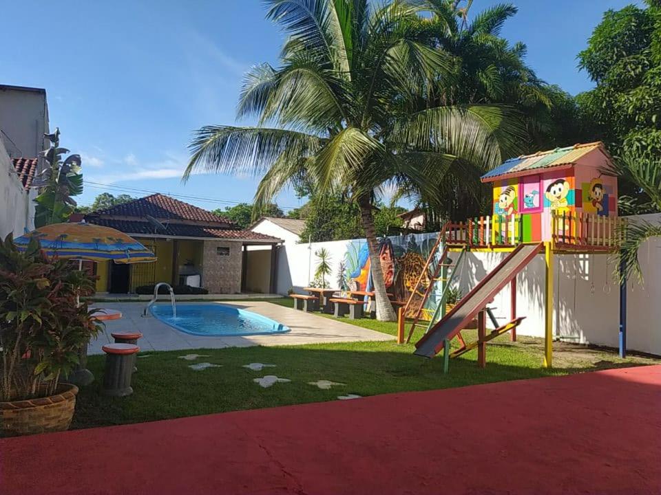 een achtertuin met een speeltuin met een glijbaan en een huis bij Recanto das Palmeiras Alter do Chão in Alter do Chao