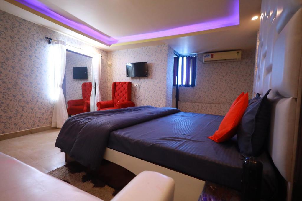 a bedroom with a bed and two red chairs at Raj Resort in Patna