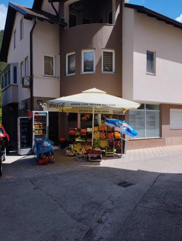 a fruit stand with an umbrella in front of a building at Apartman Šljivo in Konjic