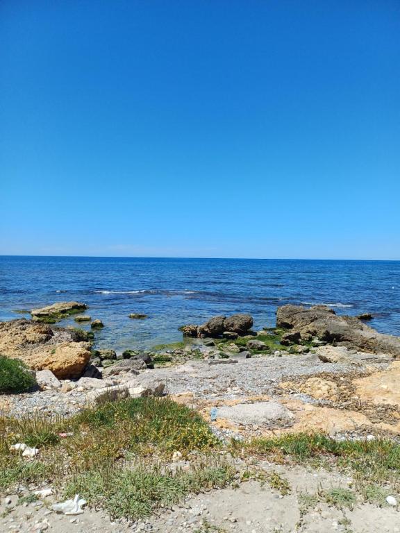 a beach with rocks and the ocean on a sunny day at Le due conchiglie in Carini