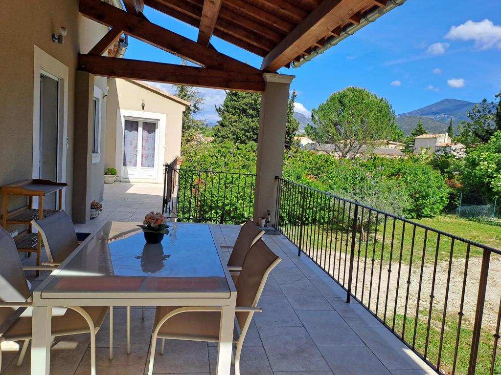 eine Terrasse mit einem Tisch und Stühlen auf dem Balkon in der Unterkunft Villa La Patachou in Malaucène