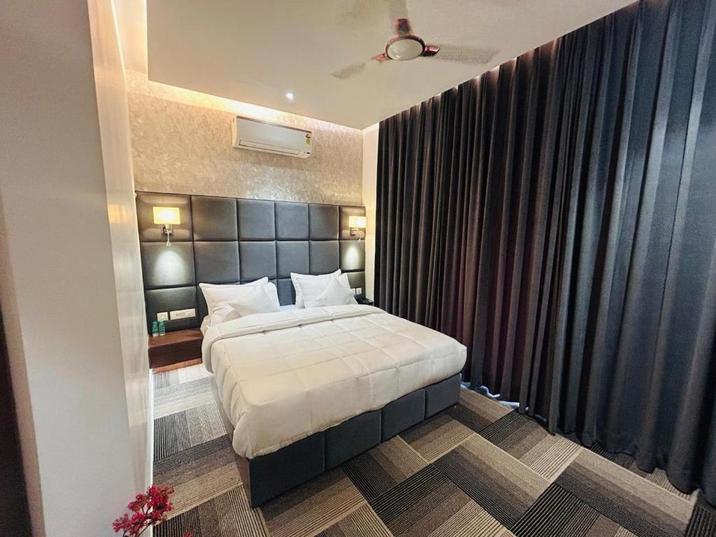 a bedroom with a large bed with a black headboard at Eminence The Corbett in Jhirna