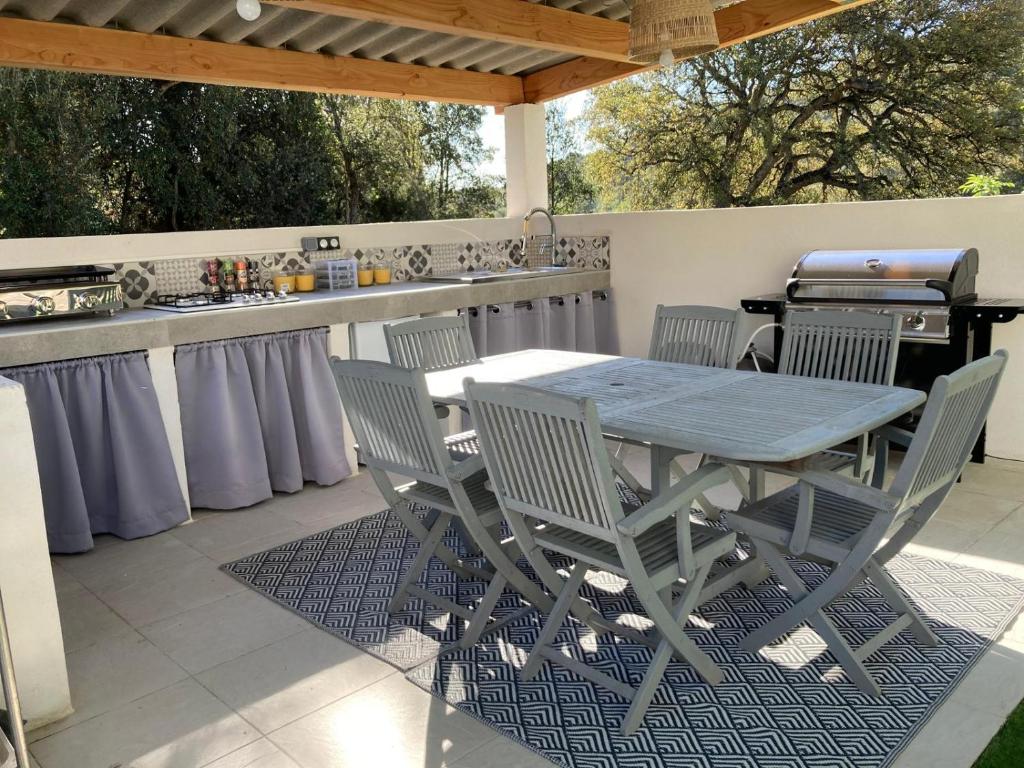 einen Tisch und Stühle auf einer Terrasse mit Grill in der Unterkunft Les jardins de funtanone T4 in Vignale