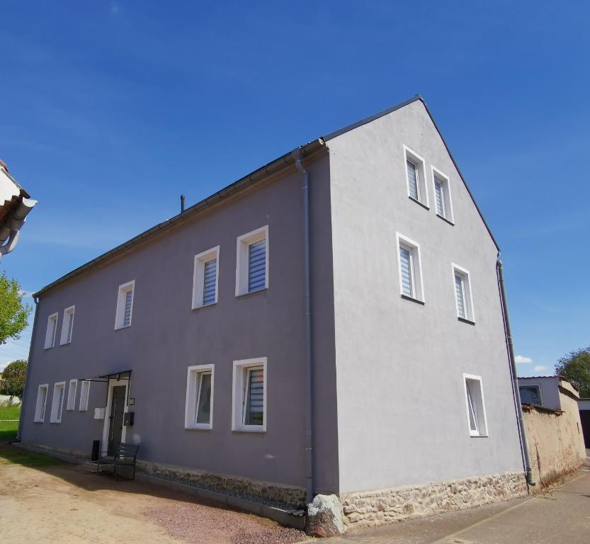 un grand bâtiment gris et blanc dans une rue dans l'établissement Airbnb, moderne, ruhige und helle Doppelzimmer, nähe Magdeburg, A14 & A2, à Dahlenwarsleben