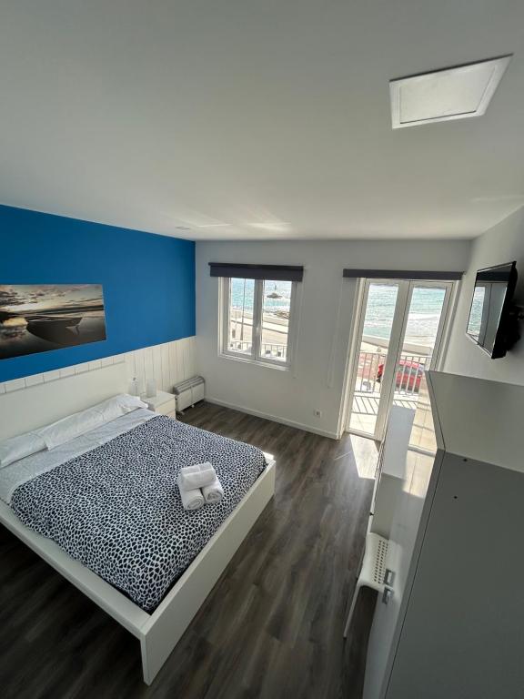 a bedroom with a bed with a blue wall at Alojamientos Plaza Portugal in Sanxenxo