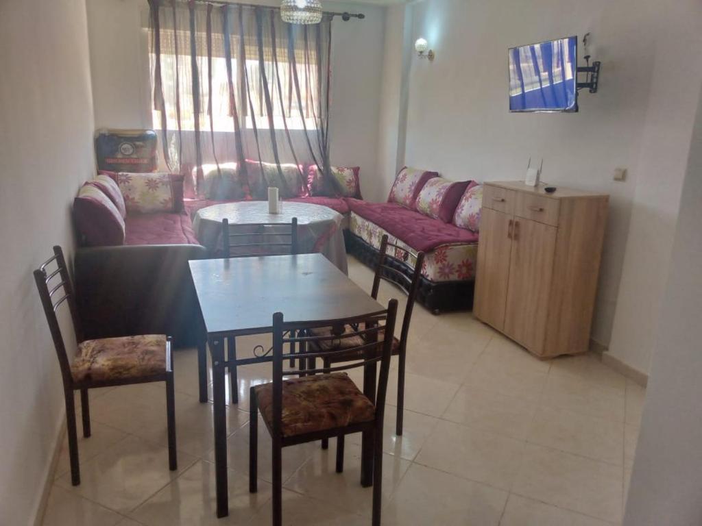 un soggiorno con tavolo, sedie e divano di Calmehome a Oujda