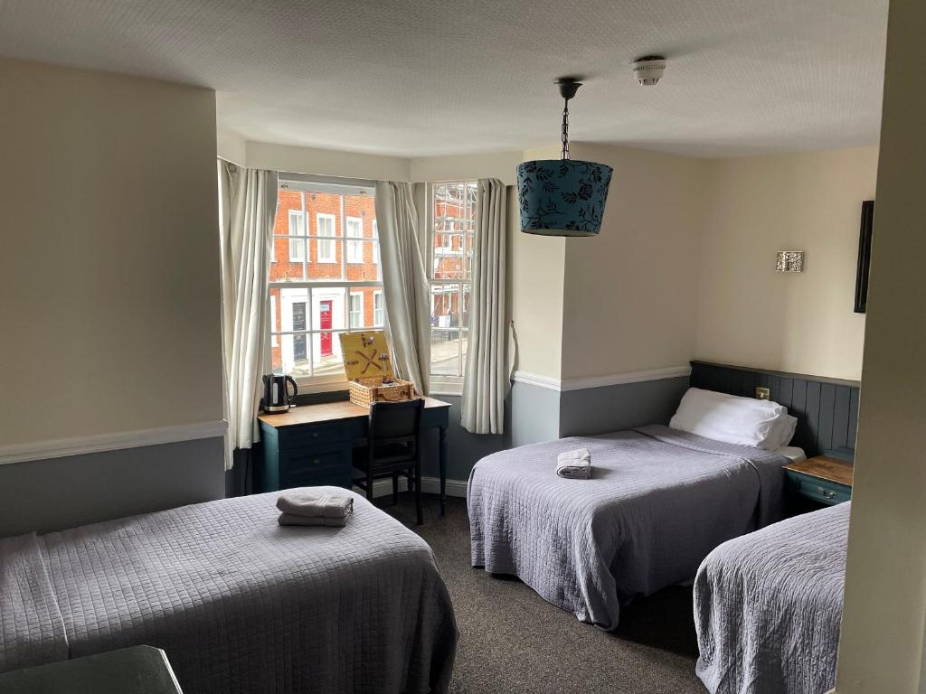 um quarto com 2 camas, uma secretária e uma janela em The Olde Swan Hotel em Chertsey