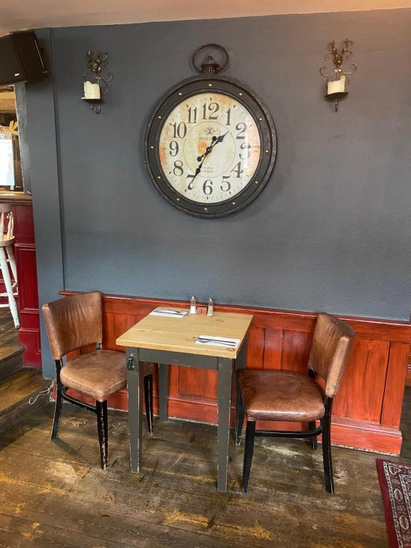 a table and chairs with a clock on the wall at The Olde Swan Hotel in Chertsey