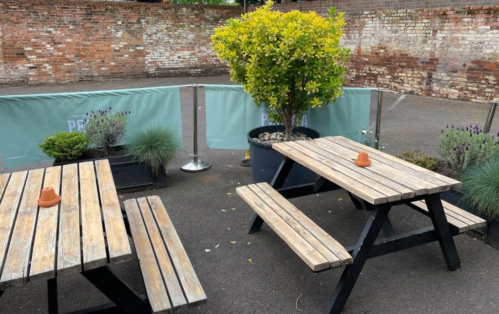 two wooden benches and a picnic table in a garden at The Olde Swan Hotel in Chertsey