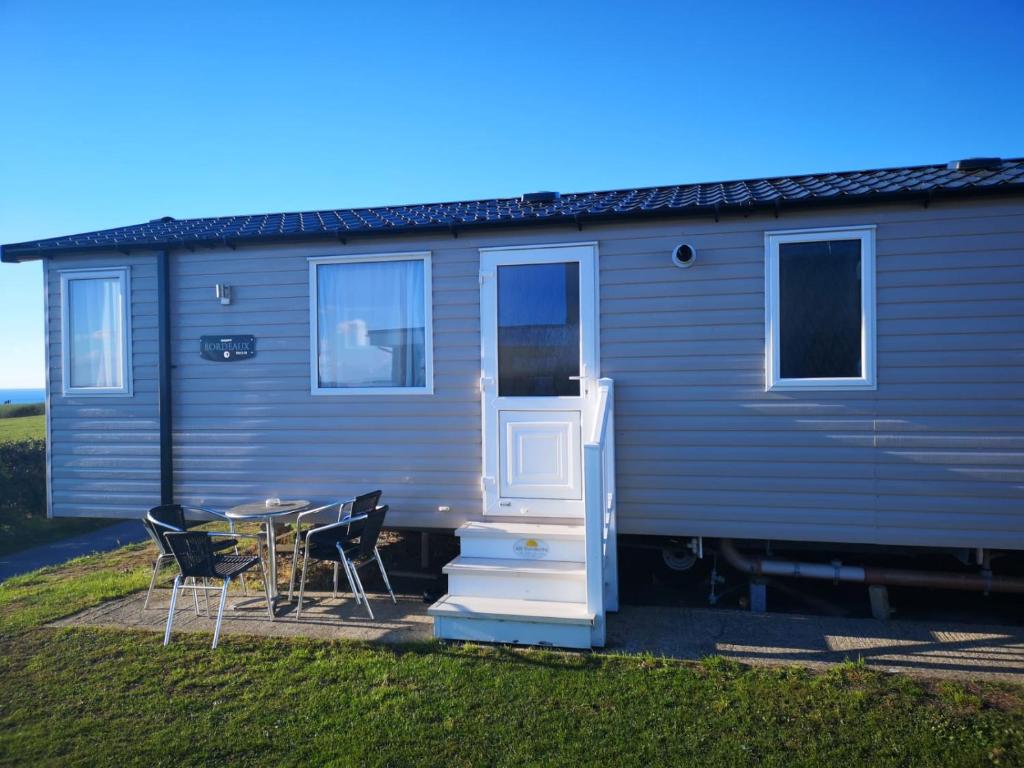 a blue tiny house with a table and chairs at B1 - Pebble Bank Caravan Park in Weymouth