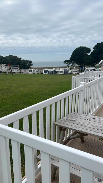 a wooden picnic table on a white porch with a field at T23- Pebble Bank Caravan Park in Weymouth