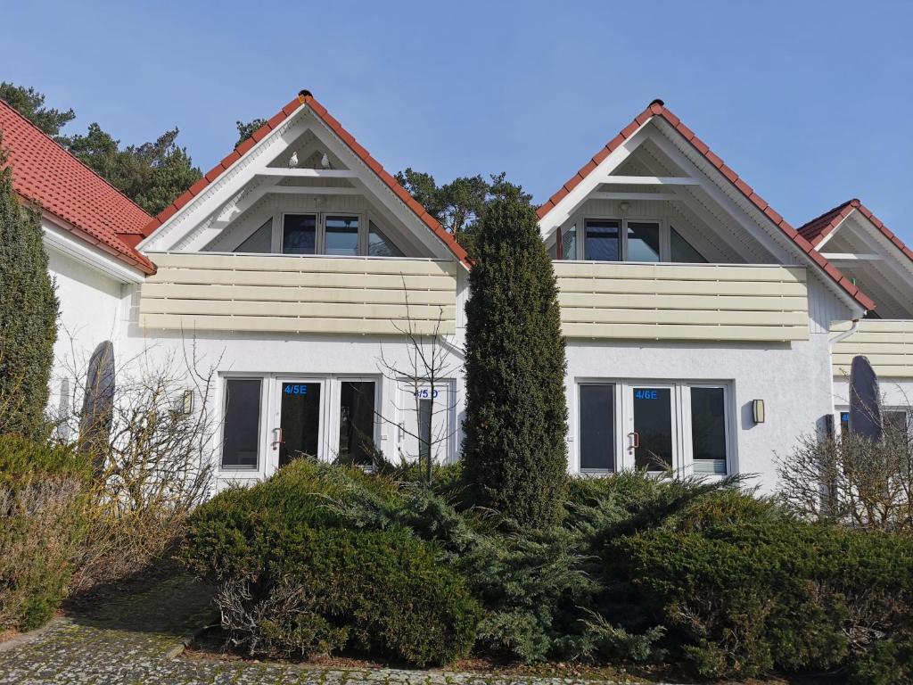 uma casa branca com um telhado vermelho em Ferienanlage "Haus hinter den Dünen" Prerow em Prerow