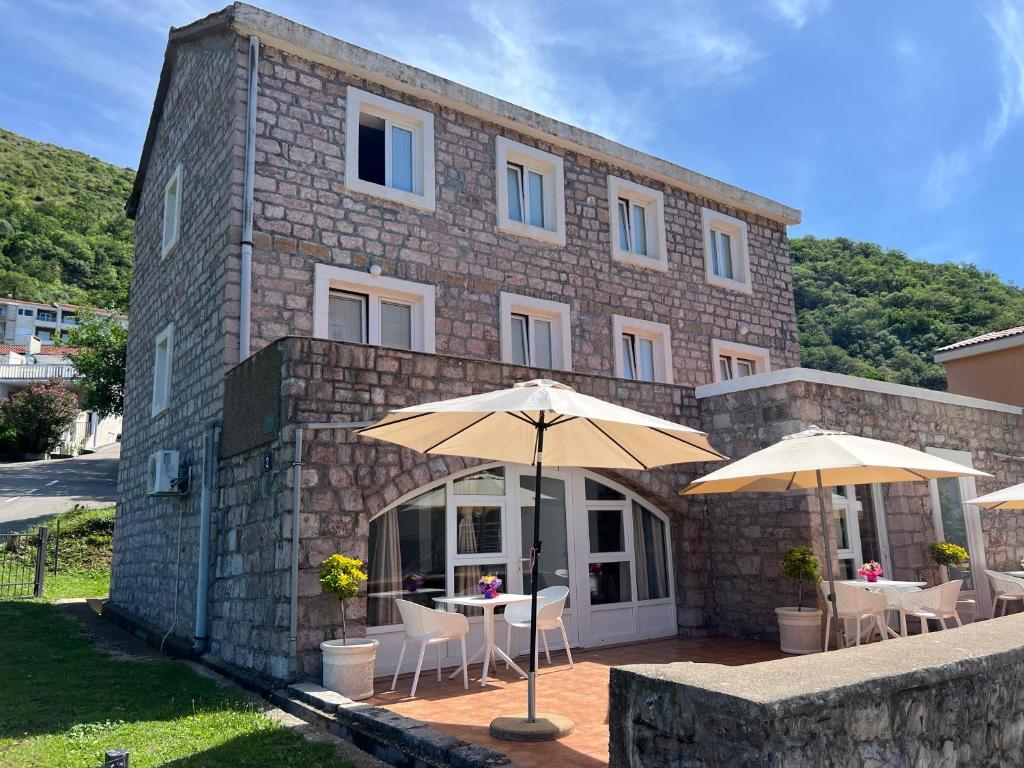 a building with tables and umbrellas in front of it at Apartments Pavlovic in Petrovac na Moru