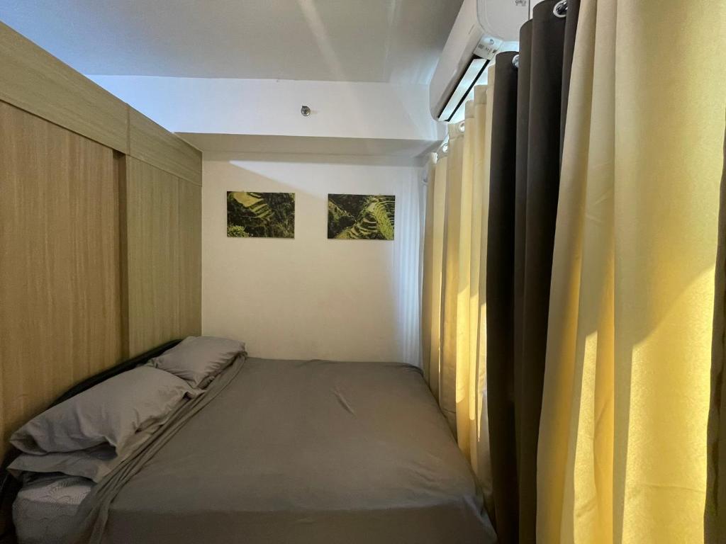 ein kleines Zimmer mit einem Bett und einem Fenster in der Unterkunft Grace Residences Pool View Free Wi-Fi near BGC and McKinley 2050 in Manila