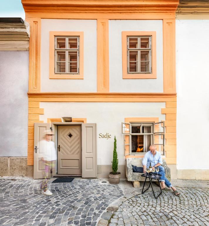 a man sitting on a chair in front of a building at Sadje in Rust