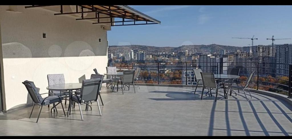 een patio met tafels en stoelen bovenop een gebouw bij Элеганс in Tbilisi City