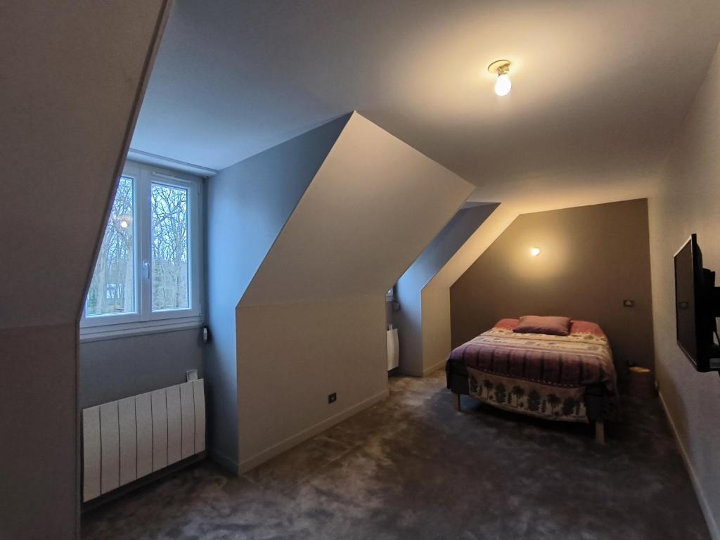Schlafzimmer im Dachgeschoss mit einem Bett und einem Fenster in der Unterkunft Etage complet in Gouvieux