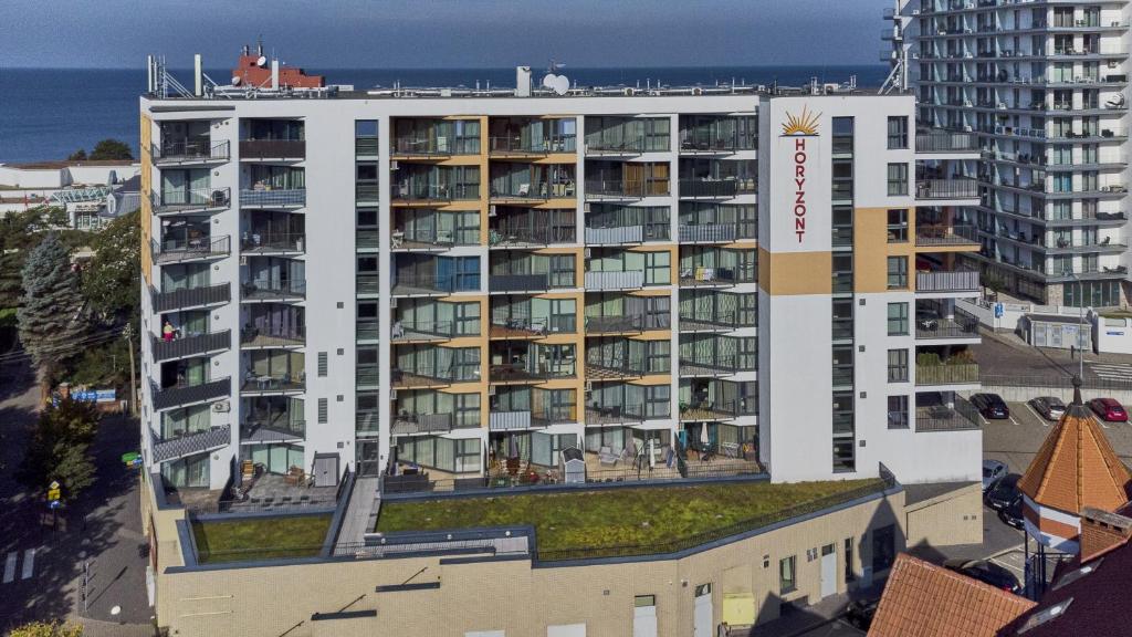 ein großes weißes Wohnhaus mit einem grünen Dach in der Unterkunft Horyzont by Baltic Home in Misdroy