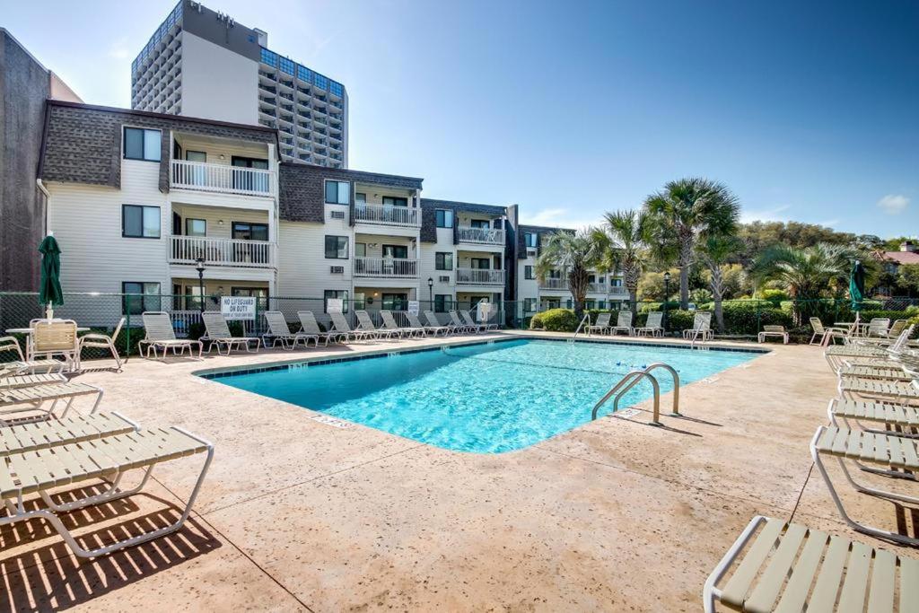 a swimming pool with chairs and a building at Matilda's at Ocean Forest Villas in Myrtle Beach