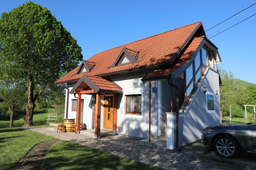een klein wit huis met een oranje dak bij Apartment Filomena in Smoljanac