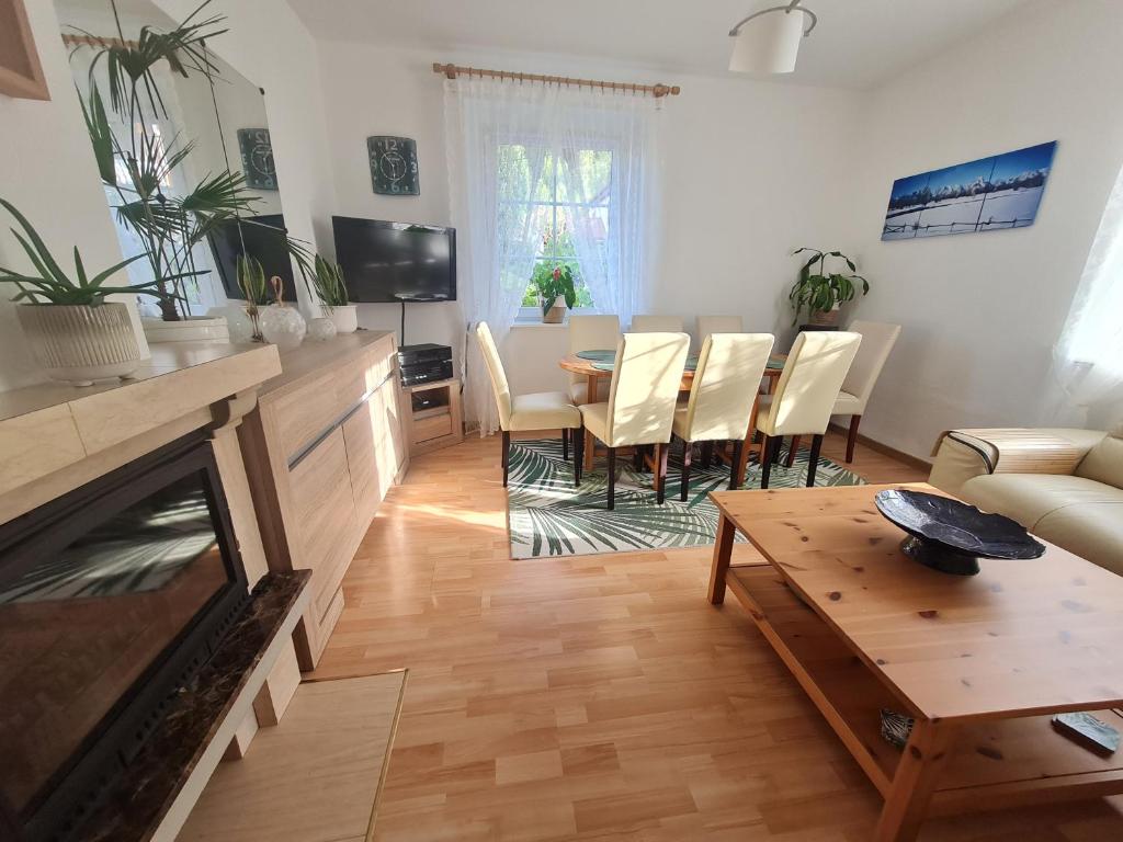 uma sala de estar com lareira e uma mesa e cadeiras em Apartament Leśna z ogrodem em Szklarska Poręba