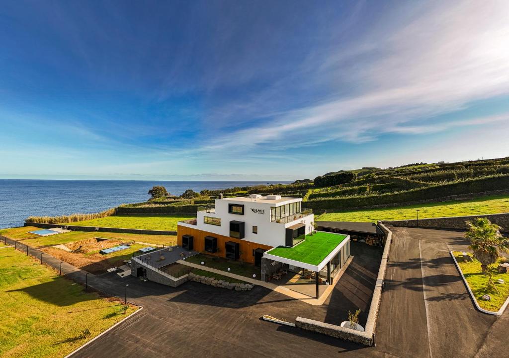 ein weißes Haus mit einem grünen Dach am Meer in der Unterkunft Xhale Azores in Angra do Heroísmo