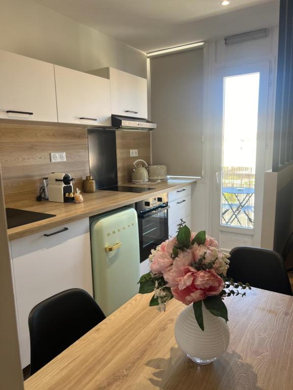 une cuisine avec une table et un vase de fleurs. dans l'établissement Joli studio spacieux, à Ajaccio