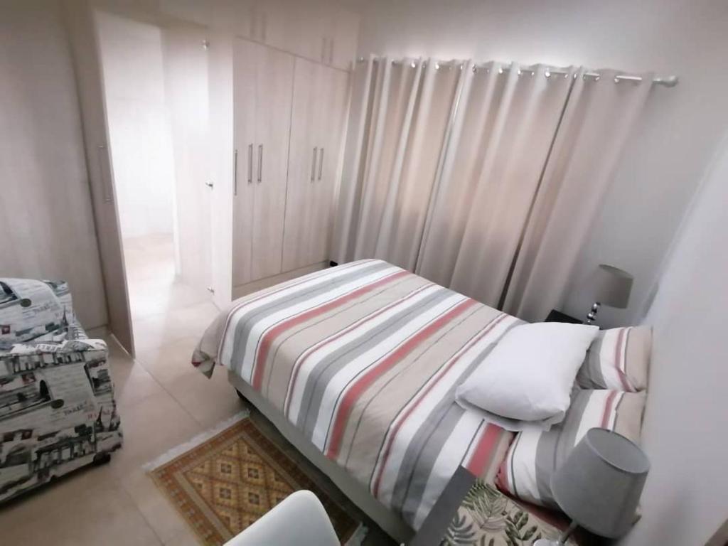 ein kleines Schlafzimmer mit einem Bett mit gestreifter Decke in der Unterkunft Seashell Haven Hideout in Henties Bay