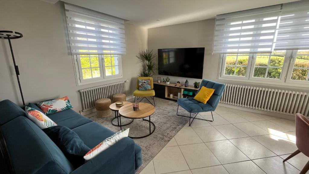 sala de estar con sofá azul y TV en Maison familiale face à la mer, en Regnéville-sur-Mer